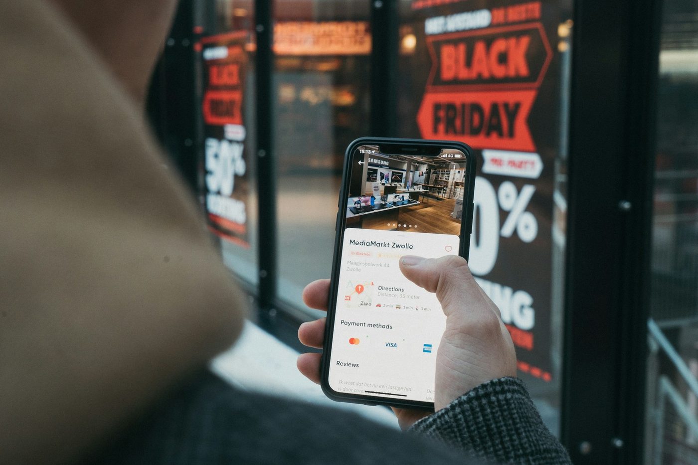 Phone displaying an online store in front of a promotional shop window