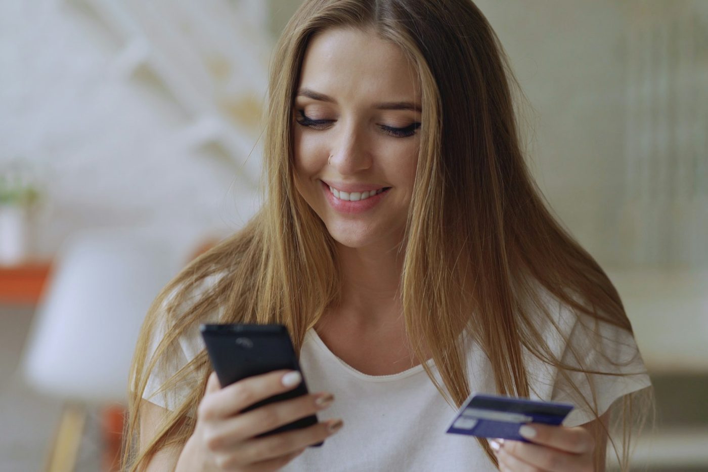 Femme tenant un téléphone et une carte bancaire